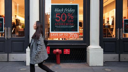 A pedestrian passes by a Black Friday discount sign at a Joe Fresh retail store in New York.