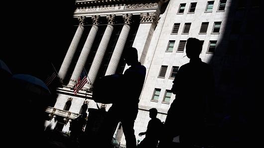 The silhouettes of pedestrians are seen passing in front of the New York Stock Exchange in New York.