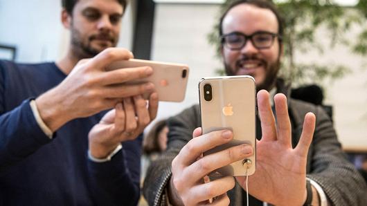 A member of staff photographs a customer as he checks the new iPhone X upon its U.K release in the Apple store, on November 3, 2017 in London, England.