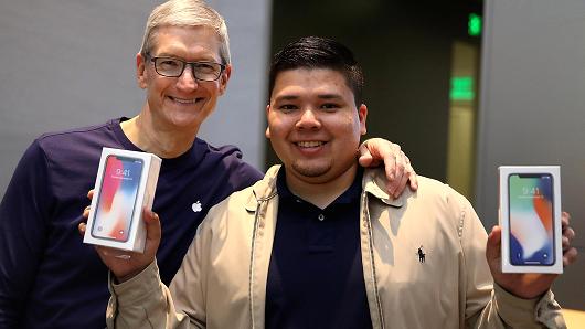 Apple CEO Tim Cook (L) takes a picture with David Casarez (R) who just purchased the new iPhone X at an Apple Store on November 3, 2017 in Palo Alto, California.