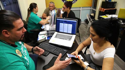 Ulysses Hernandez (L), an insurance agent from Sunshine Life and Health Advisors, speaks with Yuricel Duran as she shops for insurance under the Affordable Care Act at a store setup in the Mall of Americas on November 1, 2017 in Miami, Florida.