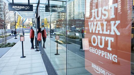 Employees stand outside the new Amazon Go grocery store in Seattle, Washington.