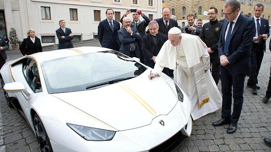 Pope Francis writes on the bonnet of a Lamborghini donated to him by the luxury sports car maker, at the Vatican, Wednesday, Nov. 15, 2017. The car will be auctioned off by Sotheby's, with the proceeds going to charities including one aimed at helping rebuild Christian communities in Iraq that were devastated by the Islamic State group.