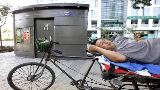 A vendor takes a nap beside a public 'bomb-proof' toilet in Beijing's Zhongguancun 'Silicon Valley' area, 06 September 2006. It was reported 06 September that the toilet, which has received a fair amount of interest in the Chinese and Hong Kong press, cost over 800,000 yuan (100,000 USD), has 30cm (10 inch) thick walls and features automatic flushing and sterilising. According to Hong Kong's South China Morning Post, who quoted a top city criminal investigator, the toilet could be strong enough to protect users from a bomb blast.