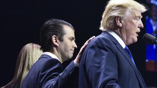 Donald Trump, Jr., (L) places a hand on the shoulder of his father, then-Republican presidential nominee Donald Trump, during in a rally in Manchester, New Hampshire on November 7, 2016.