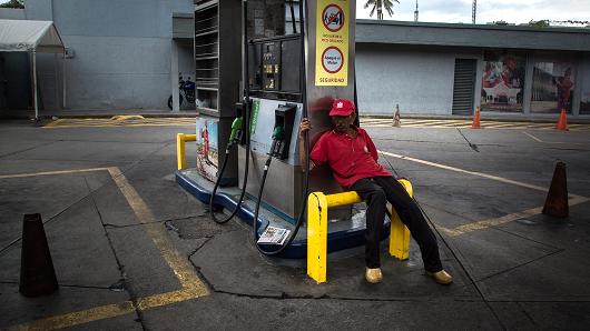 An attendant sits at a closed Petroleos de Venezuela SA (PDVSA) gas station in Caracas, Venezuela, on Friday, Sept. 22, 2017.