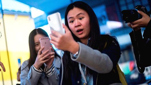 A Chinese woman reacts while setting up the facial recognition feature on her iPhone X inside an Apple showroom in Beijing on November 3, 2017.