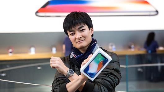 The first customer to the Apple Omotesando store holds a box containing his iPhone X as he poses to the media on November 3, 2017 in Tokyo, Japan.