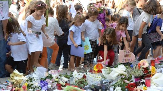 Children place cards and flowers at an informal memorial site as thousands gather during a national rally to demand justice for murdered Maltese journalist and anti-corruption blogger Daphne Caruana Galizia in the island's capital Valletta on October 22, 2017.