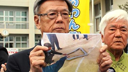 Okinawa Governor Takeshi Onaga shows a photo of a window claimed to have fallen from a U.S. helicopter.