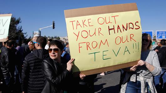 Israeli employees of Teva, the world's biggest manufacturer of generic drugs, hold placard during a protest in the centre of Jerusalem on December 17, 2017, against plans by the pharmaceutical giant to shed employees