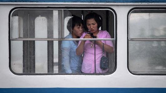Women look at a mobile phone as they ride a tram in Pyongyang, North Korea.