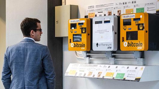 A man looks at ATM machines (L and R) for digital currency Bitcoin in Hong Kong on December 18, 2017.