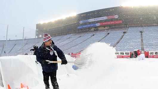 An ice crew member shovels snow Wednesday during the 2014 Bridgestone NHL Winter Classic at Michigan Stadium in Ann Arbor, Jan 1, 2014.