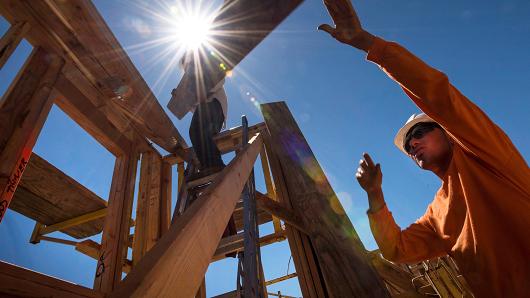 Workers load wood planks on a house under construction in Livermore, California.