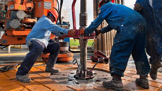 Oil workers make a pipe connection on a drilling rig near Encinal, Texas.