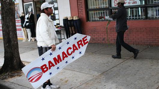 Pedro Rojas holds a sign directing people to an insurance company where they can sign up for the Affordable Care Act, also known as Obamacare