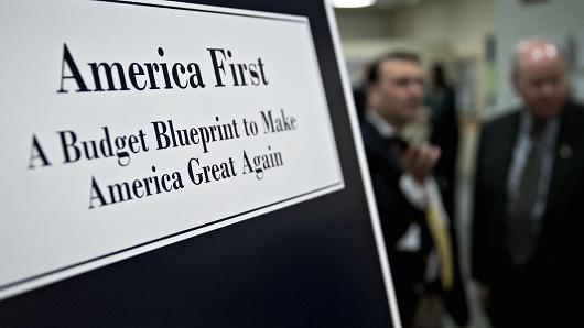 A poster of U.S. President Donald Trump's fiscal 2018 budget request, America First: A Budget Blueprint to Make America Great Again, stands on display at the Government Printing Office (GPO) library in Washington, D.C., U.S., on Thursday, March 16, 2017.