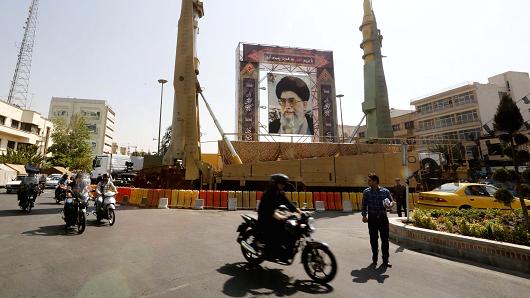 Iranians walk past Sejjil (L) and Qadr-H medium range ballistic missiles displayed next to a portrait of Iranian Supreme Leader Ayatollah Ali Khamenei on September 25, 2017, on Baharestan square in Tehran.