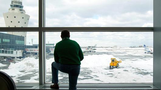 A traveler watches a crew remove snow in the Central Terminal at LaGuardia Airport in the Queens borough of New York.