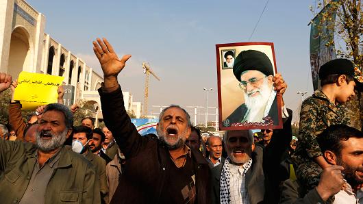 Pro-government demonstrators hold a poster of Iran's supreme leader Ayatollah Ali Khamenei during a march following the weekly Muslim Friday prayers in Tehran on January 5, 2018.