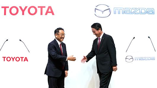 Toyota Motor Co. President Akio Toyoda, left, and Mazda Motor Co. President and CEO Masamichi Kogai, right, shake hands during a photo session at a joint press conference on August 4, 2017 in Tokyo, Japan.