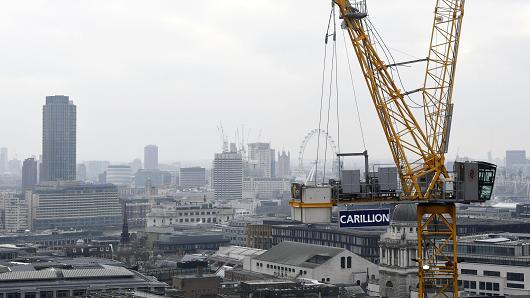 A construction crane showing the branding of British construction company Carillion is photographed on a building site in central London on January 14, 2018, with the skyline of the British capital in the background including the London Eye and the Houses of Parliament.