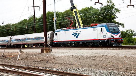 A new Siemens-built Amtrak Cities Sprinter locomotive passes work crews in Hamilton, N.J., where a new substation and catenary system will support future high-speed rail.