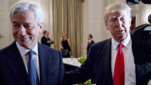 In this 2017 file photo, President Donald Trump stands next to Jamie Dimon, chief executive officer of JPMorgan Chase & Co., left, in the State Dining Room of the White House in Washington.
