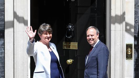Arlene Foster, leader of the Democratic Unionist Party (DUP), left, waves as Nigel Dodds, deputy leader of the Democratic Unionist Party (DUP), looks on as they pose for photographers on the steps of number 10 Downing Street, during their arrival for a meeting with U.K. Prime Minister Theresa May, in London, U.K., on Tuesday, June 13, 2017.