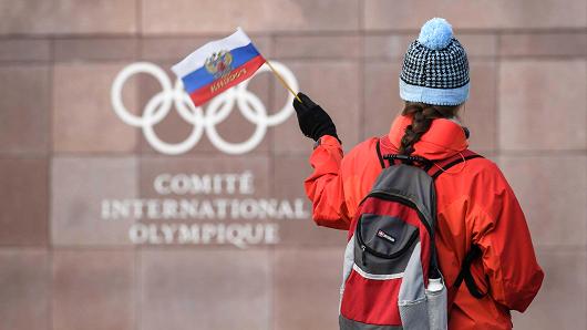 A supporter waves a Russian flag in front of the logo of the International Olympic Committee (IOC) at their headquarters on December 5, 2017 in Pully near Lausanne, Switzerland.