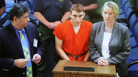 Nikolas Cruz (C) appears via video monitor with Melisa McNeill (R), his public defender, at a bond court hearing after being charged with 17 counts of premeditated murder, in Fort Lauderdale, Florida, U.S., February 15, 2018.