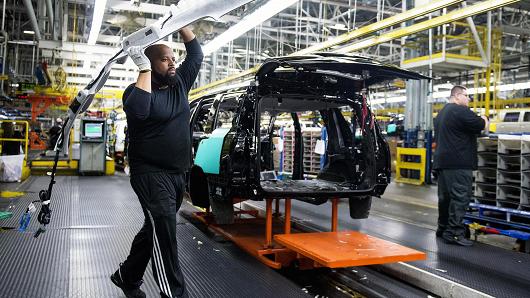 An employee carries a headliner to be installed onto a vehicle at the General Motors assembly plant in Arlington, Texas.
