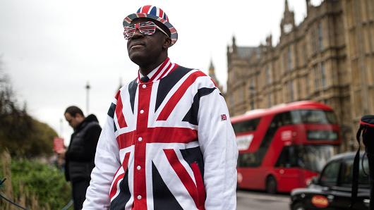A man wearing clothing featuring the Union flag stands in front of the Houses of Parliament in London, on March 29, 2017.