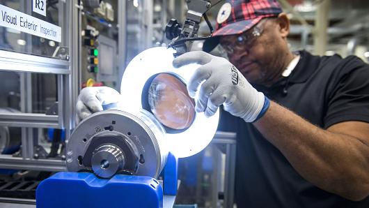 An employee inspects a component for hybrid electric vehicle motors at the Toshiba International manufacturing facility in Houston, Texas.