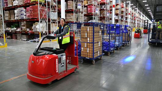 A worker pulls carts full of customer orders along the floor inside the million-square foot Amazon distribution warehouse that opened last fall in Fall River, MA.