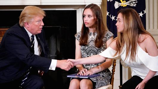 President Donald Trump shakes hands with Marjory Stoneman Douglas High School student Ariana Klein (R) watched by fellow student Carson Abt at the start of a listening session on gun violence with teachers and students in the State Dining Room of the White House on February 21, 2018.