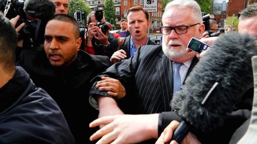 Paul Flowers, former chairman of Co-Operative Bank Plc, right, is surrounded by media as he leaves Leeds Magistrates Court in Leeds, U.K., on Wednesday, May 7, 2014.