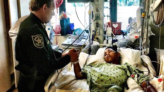 This image made available by the Broward County Sheriff's Office on Sunday, Feb. 18, 2018, shows Sheriff Scott Israel, holding the hand of Anthony Borges, 15, a student at Marjory Stoneman Douglas High School. The teenager was shot five times during the massacre on Valentine's Day that killed 17 students. Borges is being credited with saving the lives of at least 20 other students.