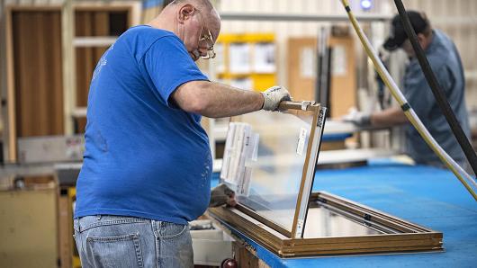 A worker installs glass to a window frame at the Pella Corp. manufacturing facility in Pella, Iowa.