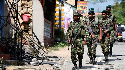 Sri Lanka's Special Task Force soldiers walk past a damaged houses after a clash between two communities in Digana central district of Kandy, Sri Lanka March 8, 2018.