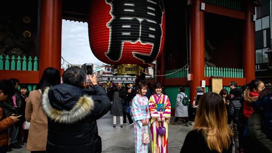 Tourists in kimonos have their photograph taken next to a huge lantern in Senso-ji buddhist temple, on January 19, 2018, in Tokyo.