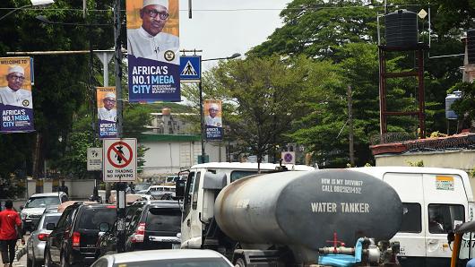 Motorists wait in traffic under banners bearing portraits of Nigerian President Muhammadu Buhari on March 29, 2018, in Lagos, Nigeria.