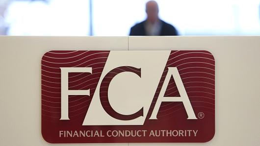 A logo sits on a sign in the reception area of the headquarters of the Financial Conduct Authority (FCA) in the Canary Wharf business district in London, U.K.