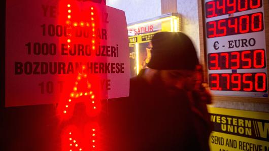 People walk past a sign offering customers a 10TL gift if they exchange more than $1,000 or euro at a currency exchange store on December 5, 2016, in Istanbul.