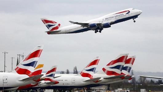 A Boeing Co. 747 passenger aircraft, operated by British Airways, a unit of International Consolidated Airlines Group SA (IAG), takes off over a row of passenger aircraft operated by British Airways at Heathrow airport in London, U.K.