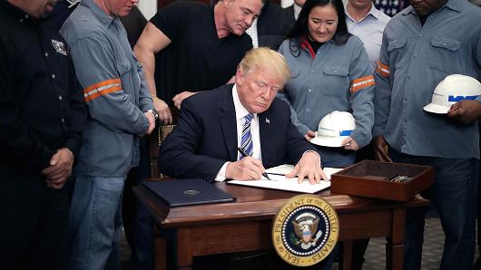 Surrounded by steel and aluminum workers, U.S. President Donald Trump (C) signs a 'Section 232 Proclamation' on steel imports during a ceremony in Roosevelt Room the the White House March 8, 2018 in Washington, DC.
