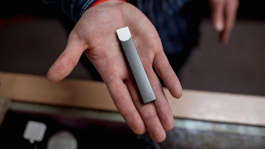 Ryan Purington, an employee at Lucky Juju, holds a JUUL vape in his hand. The store started stocking the vapes last month and Purington said that they are 'flying off' the shelves because they are discreet, easy to use and powerful.