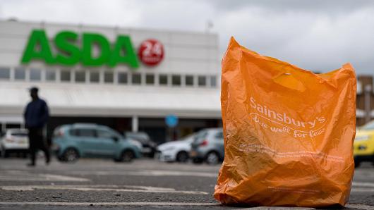 In this arranged photo illustration, a Sainsbury's shopping bag is seen on the ground in the car park of an Asda supermarket on April 29, 2018 in London, England. Major supermarket chains Sainsbury's and Asda have been reported to be in talks over a £10 billion merger deal which would mean the possible new supermarket group would have 31.4% market share, compared with Tesco's 25.6%.