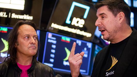 John Legere, chief executive officer and president of T-Mobile US Inc., left, listens as Marcelo Claure, chief executive officer of Sprint Corp., speaks during an interview on the floor of the New York Stock Exchange (NYSE) in New York, U.S., on Monday, April 30, 2018.